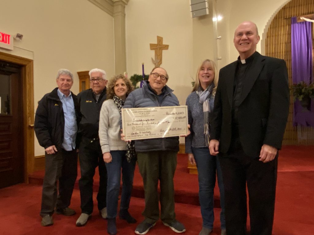 Dinner committee presenting the food pantry check to Fr. Ken.