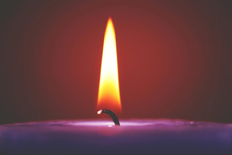 Close-up of a glowing candle flame against a dark background, creating a warm ambiance.